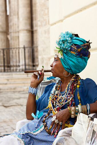 Havana, Cuba – August 7, 2016: Colorful dressed woman smoking a cuban cigar at Havana´s main square.