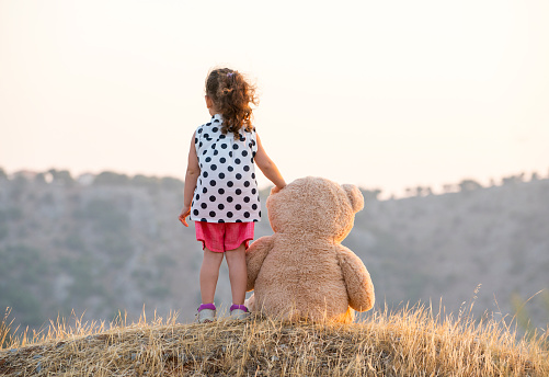 Little girl in a dress stands in a room near an inflatable golden figure. High quality photo