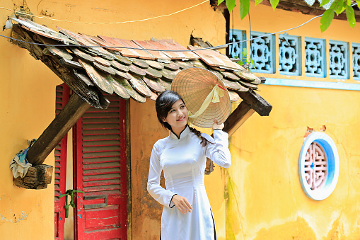 beautiful Vietnamese girl in traditional custom long dress ( Ao Dai ) with conical hat.