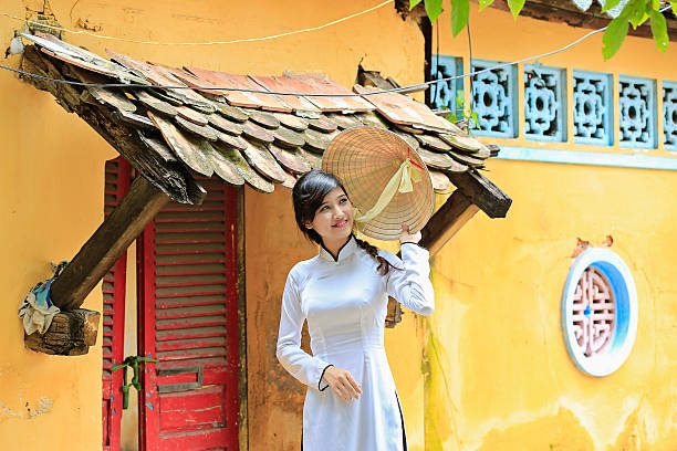 beautiful Vietnamese girl in traditional long dress  or Ao Dai beautiful Vietnamese girl in traditional custom long dress ( Ao Dai ) with conical hat. ao dai stock pictures, royalty-free photos & images