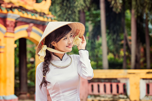 beautiful Vietnamese girl in traditional custom long dress ( Ao Dai ) with conical hat.