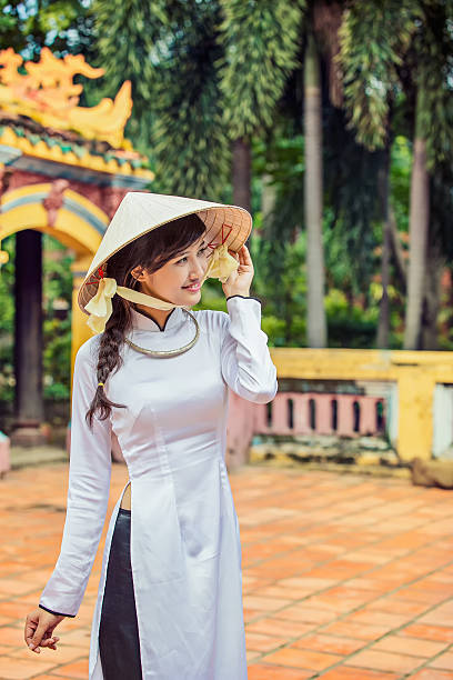 beautiful Vietnamese girl in traditional long dress or Ao Dai beautiful Vietnamese girl in traditional custom long dress ( Ao Dai ) with conical hat. ao dai stock pictures, royalty-free photos & images