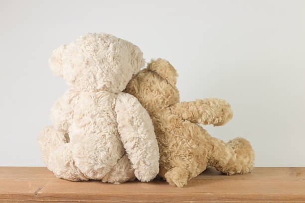 istock Two teddy bears sitting on wooden table looking something. 599904224