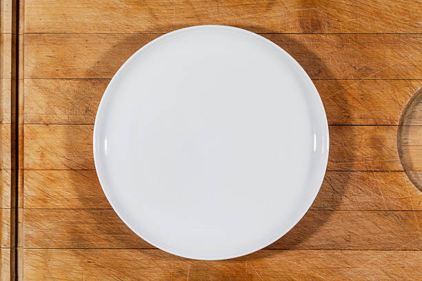 istock Flat white plate shallow on wooden cutting board from above 599904716