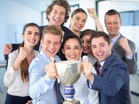 Cheerful group of businesspeople winning the cup with hands up.