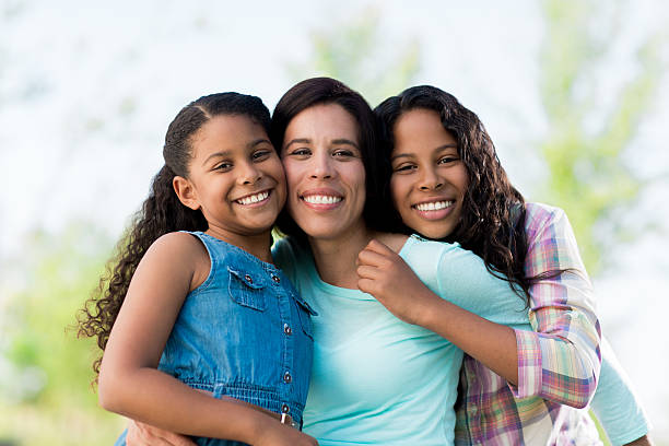 istock Mother and daughters embracing and smiling at camera 599908556