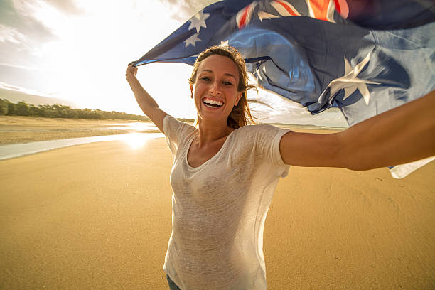 junge frau nimmt selfie-porträt am strand mit flagge - australia australia day celebration flag stock-fotos und bilder