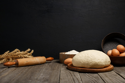 Dough on wooden table on dark background with space for an object in a bakery
