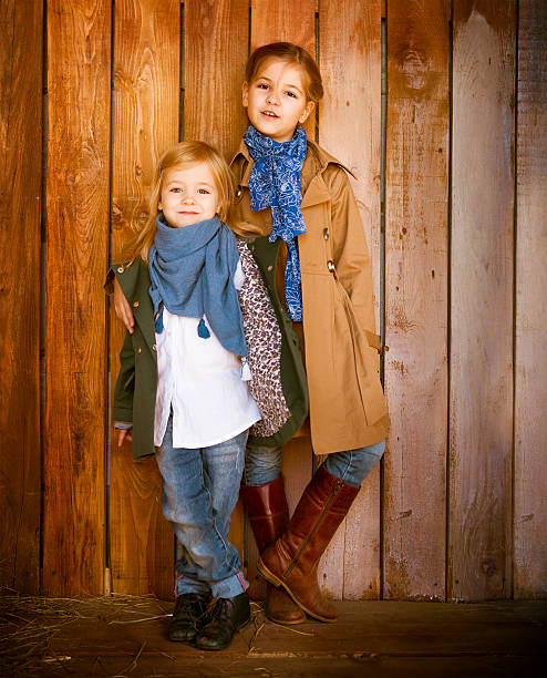 Cute little sisters wearing autumn  clothes Cute little sisters wearing autumn  clothes posing over wooden background kids winter fashion stock pictures, royalty-free photos & images