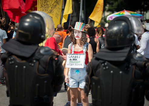 Rio de Janeiro, Brazil - September 07, 2016: Demonstration against the ruling president of Brazil, Michel Temer. Woman dressed like a clown while riot policemen watch.