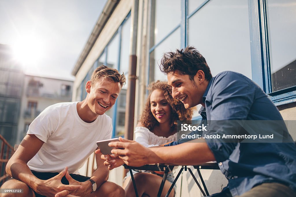 Grupo de amigos viendo video en el teléfono inteligente - Foto de stock de Amistad libre de derechos