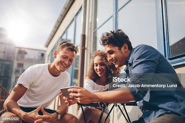 Group Of Friends Watching Video On Smartphone Stock Photo - Download Image Now - Friendship, Mobile Phone, Group Of People