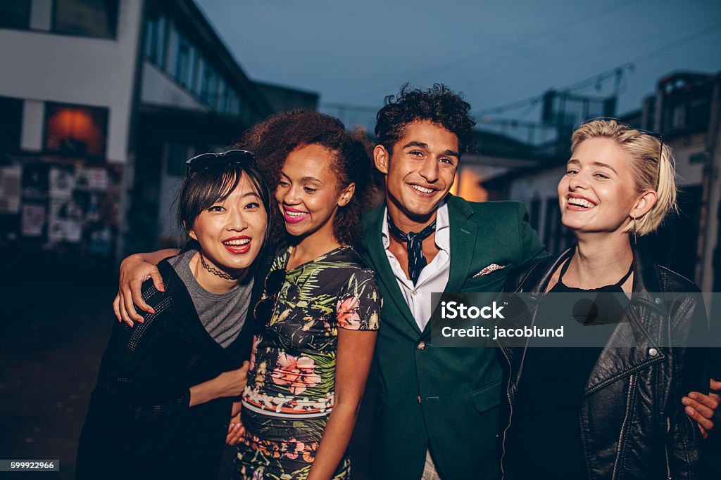 Group of friends walking on city street together at night Group of friends walking on city street together at night. Multiracial young man and women enjoying outdoors in evening. Fashion Model Stock Photo