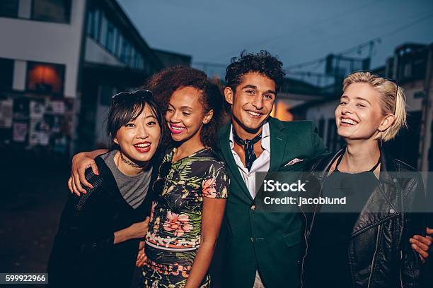 Group Of Friends Walking On City Street Together At Night Stock Photo - Download Image Now