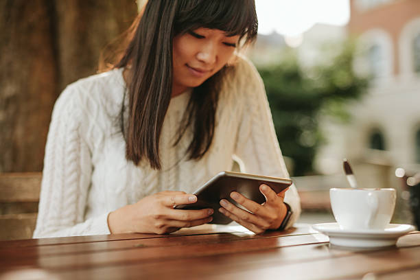 istock Chinese woman using digital tablet at outdoor cafe 599951826