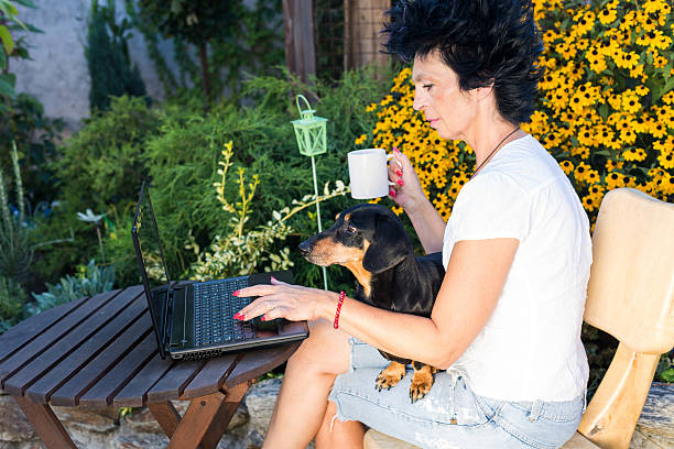 istock senior woman with dog using laptop 599954304