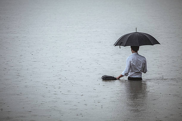 水の中に立って、雨の間に傘を持っているハンサムな男 - wading ストックフォトと画像