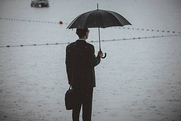 istock Handsome man wearing suit and holding umbrella during the rain 599958272