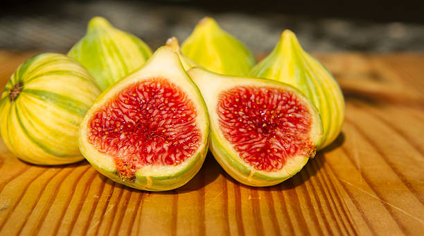 Closeup of one sliced and whole panachee variegated striped figs stock photo