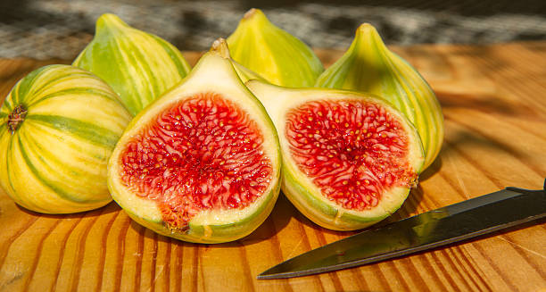 Closeup of one sliced and whole panachee striped figs stock photo