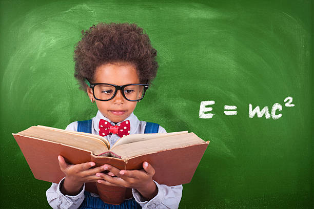 istock Schoolboy reading a book in front of school board 599959412