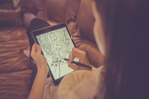 DSLR picture of Female Hands Drawing Mandala on Electronic Tablet.