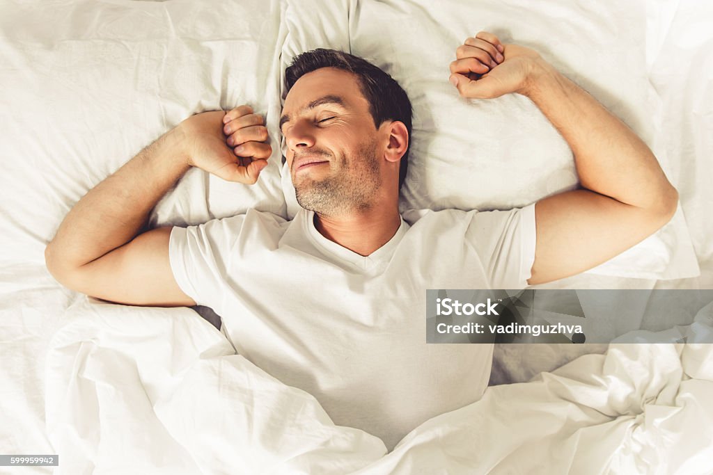 Man in the morning Top view of handsome man smiling while sleeping in his bed at home Men Stock Photo