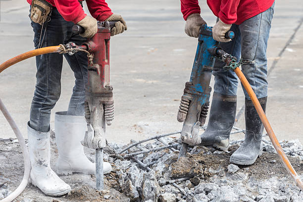 istock Construction worker removes excess concrete with drilling machin 599968646