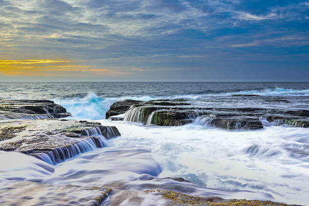 wave flows over weathered rocks and boulders at North Narrab