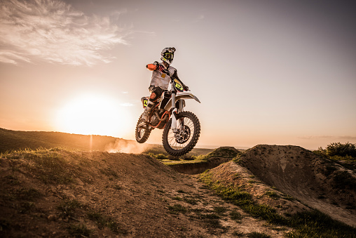 Motocross rider jumping on extreme terrain at sunset. Copy space.