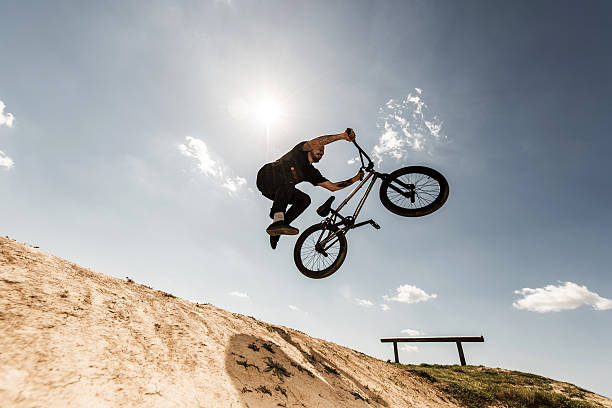 sotto la vista del ciclista bmx che salta contro il cielo. - bmx cycling bicycle cycling sport foto e immagini stock