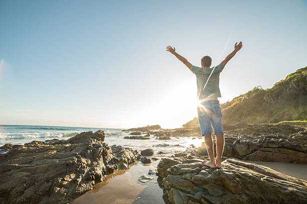 istock Caucasian man arms outstretched on the beach at sunrise 599977434