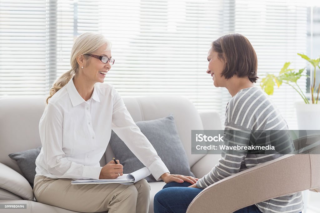 Happy therapist with patient Happy therapist with woman on sofa at home Mental Health Professional Stock Photo