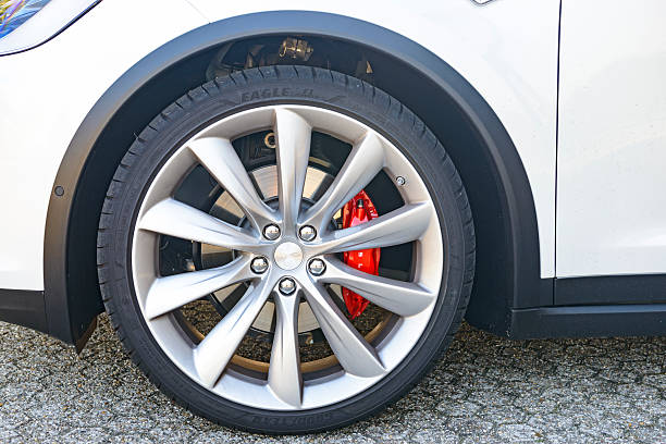 Duiven, Netherlands, The - September 7, 2016: Front wheel on a white Tesla Model X P90D all-electric crossover SUV at a Tesla dealership. The Tesla Model X is a full-sized all-electric crossover SUV made by Tesla Motors that uses falcon wing doors. Other Tesla Model S cars are parked in the background.