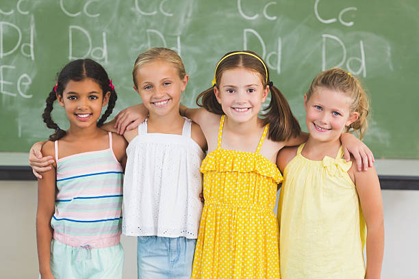 istock Smiling kids standing with arm around in classroom 599987612