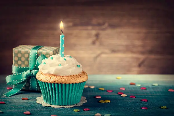 Cupcake with birthday candle and gift box