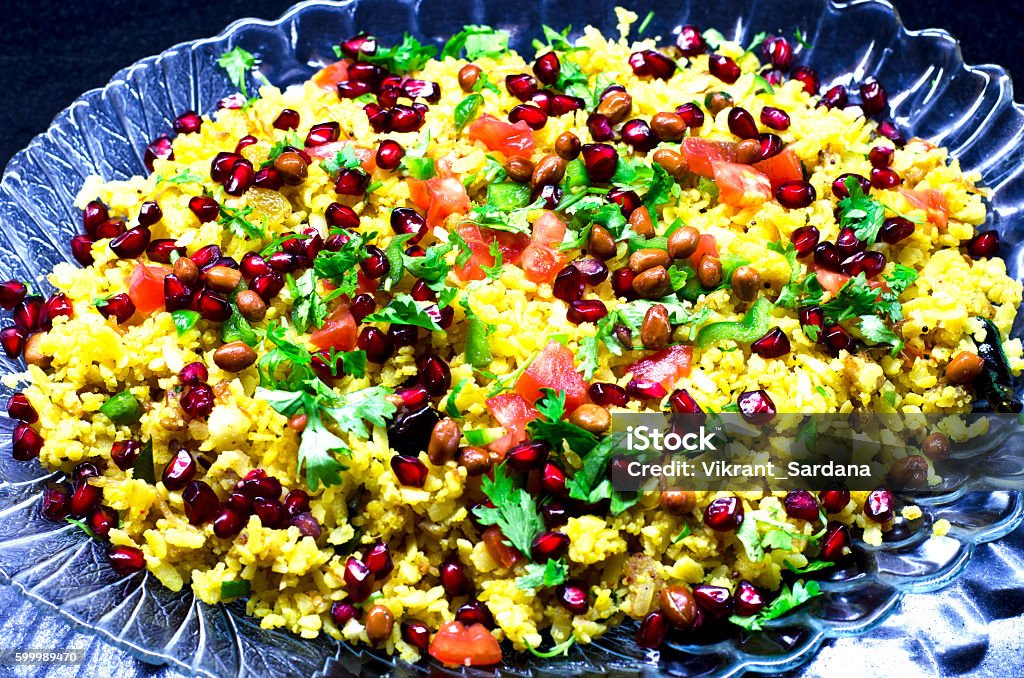 Poha, a popular Indian dish served in a tray Poha is popular vegetarian dish generally served in breakfast or as snacks. It is prepared from flattened rice and can be garnished using fried peanuts, coriander, curry leaves, pomegranate etc Pomegranate Stock Photo