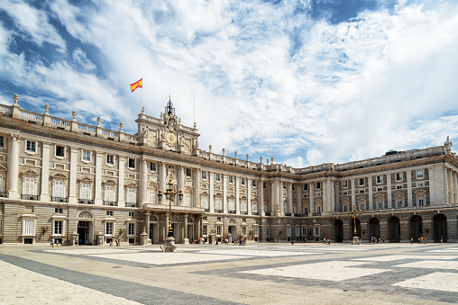 Madrid, Spain - August 18, 2014: The Plaza de la Armeria (Armory Square) and the south facade of the Royal Palace of Madrid on the blue sky background with white clouds in Spain. Madrid is a popular tourist destination of Europe.