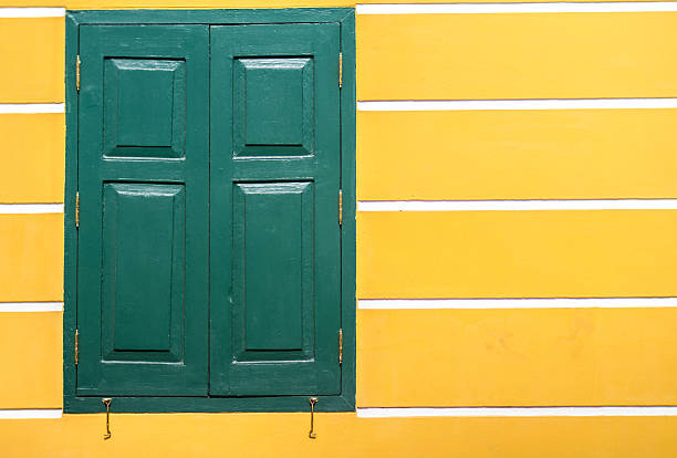 window green frame on an old yellow stucco wall with white line on background, texture, pattern, vintage