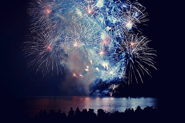 istock Beautiful large colorful fireworks display with unrecognizable crowd people watching 599993212