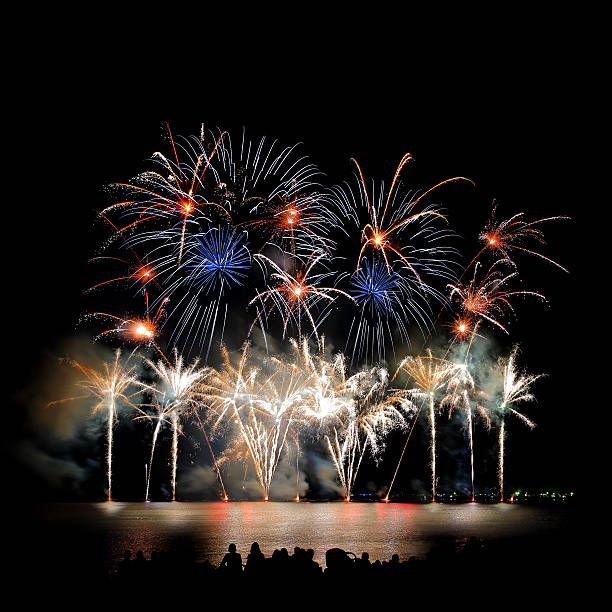 istock Beautiful large colorful fireworks display with unrecognizable crowd people watching 599994244