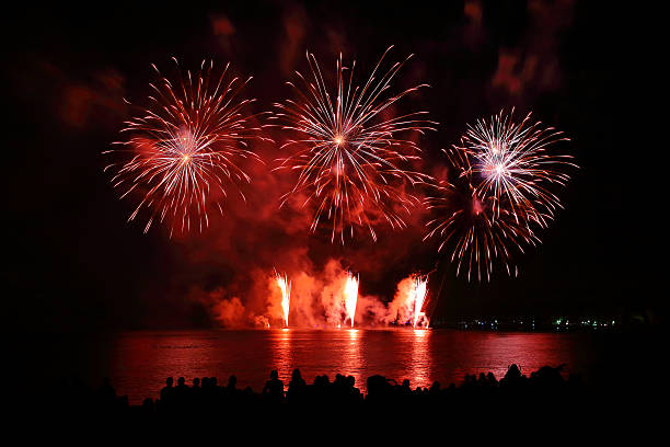 Beautiful large red fireworks display with unrecognizable crowd people watching