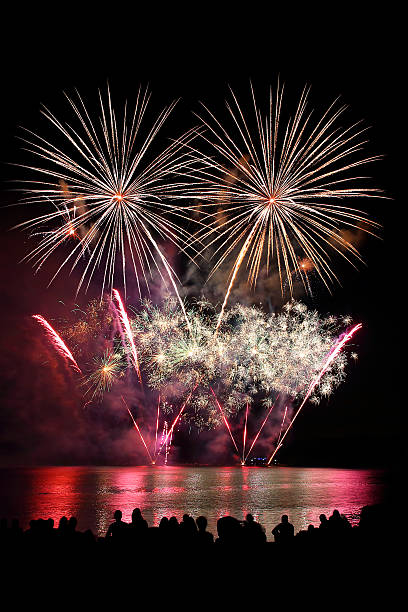 istock Beautiful large colorful fireworks display with unrecognizable crowd people watching 599996038