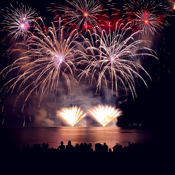 istock Beautiful large colorful fireworks display with unrecognizable crowd people watching 599996756