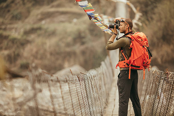 Hiker capturing the view Photo of a hiker capturing the view over the bridge in Annapurna Range on Himalayas, Nepal annapurna range photos stock pictures, royalty-free photos & images