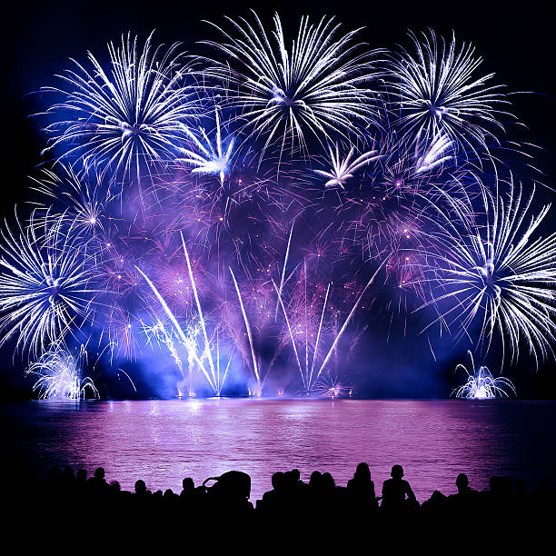 istock Beautiful large colorful fireworks display with unrecognizable crowd people watching 599999180