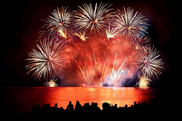 istock Beautiful large colorful fireworks display with unrecognizable crowd people watching 599999562