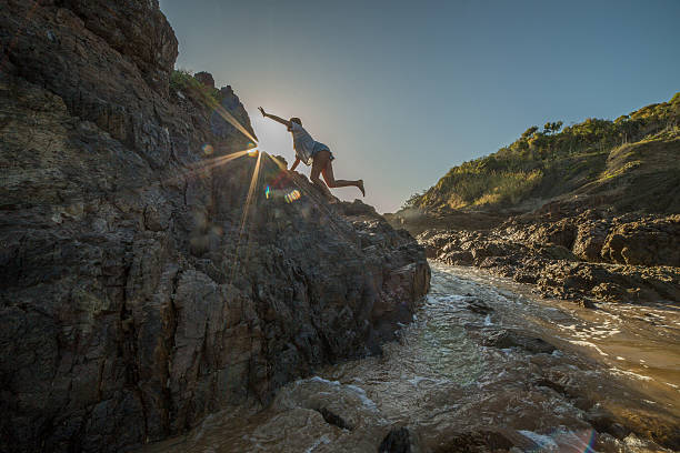 istock Young woman climbs steep rock, towards sunlight 600056426