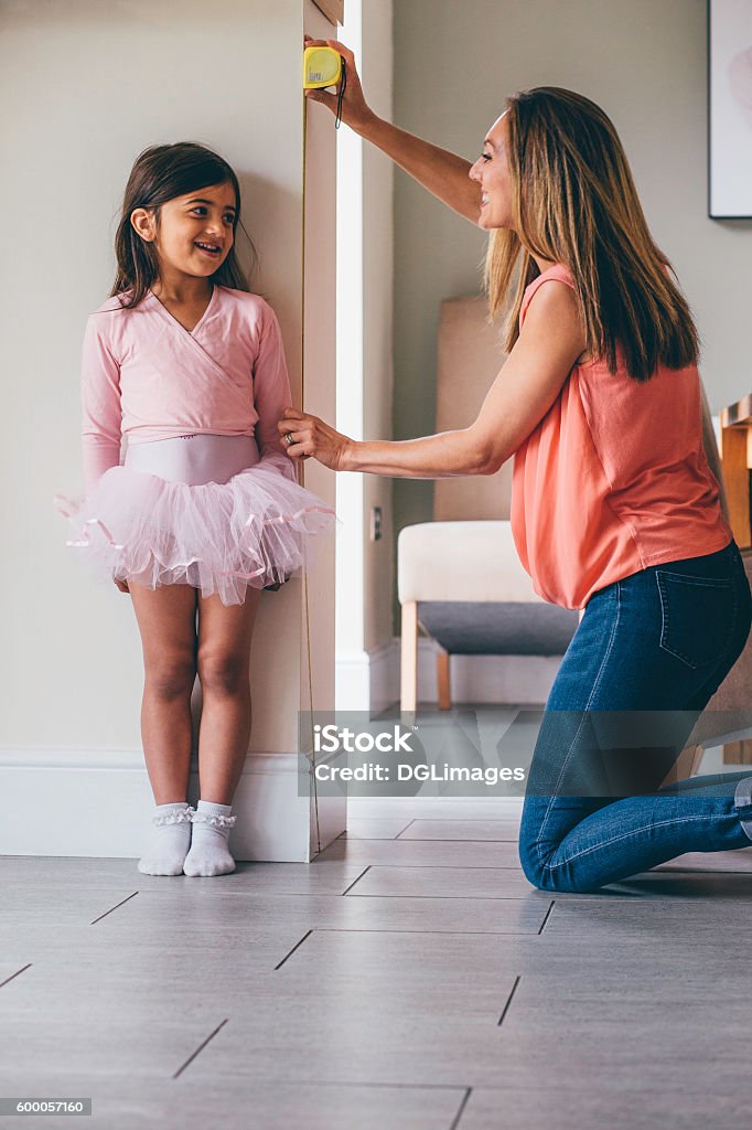 Not so little Ballerina! Little girl in a ballet costume having her height measure by her mother. She is standing against the wall whilst her mother uses the tape measure. Child Stock Photo