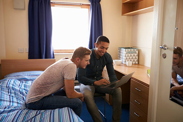 studenti maschi che lavorano nella camera da letto dell'alloggio del campus - hotel wireless technology bedroom hotel room foto e immagini stock